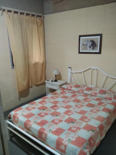 a bedroom with a bed with a red and white quilt at Estancia turistica la Providencia in Termas del Daymán