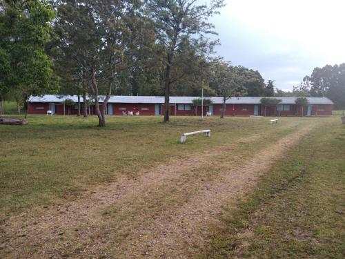 a field with a red building in the background at Estancia turistica la Providencia in Termas del Daymán