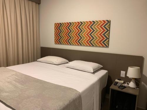 a bedroom with a bed and a painting on the wall at Park Veredas Flat 430 in Rio Quente