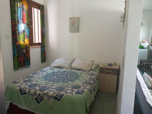 a bedroom with a bed with a quilt on it at LA CABAÑA DE HUERTAMAR in Zorritos