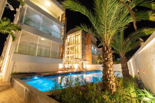 a house with a swimming pool and a palm tree at ONE BAY Residence Apartment 3 Luxury Unit Grand Baie in Pereybere