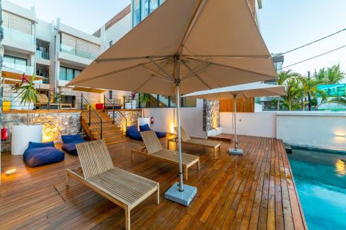a patio with chairs and an umbrella next to a pool at ONE BAY Residence Apartment 3 Luxury Unit Grand Baie in Pereybere