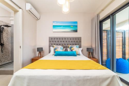 a bedroom with a large bed with yellow and blue pillows at ONE BAY Residence Apartment 3 Luxury Unit Grand Baie in Pereybere