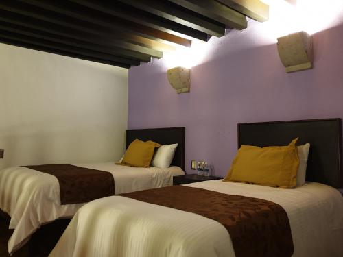 two beds in a room with purple walls at Hotel Don Carlos in Morelia