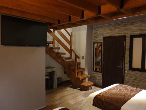 a bedroom with a staircase and a bed with a television at Hotel Don Carlos in Morelia