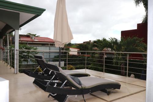 a patio with chairs and an umbrella on a balcony at 11B Jaco Sol Quadplex in Jacó