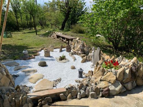 a garden with rocks and a river with a bench at R&B Mulino Marsa in CastellʼArquato