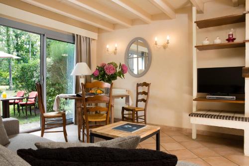 a living room with a couch and a television and a table at Cottages De La Bretesche in Missillac