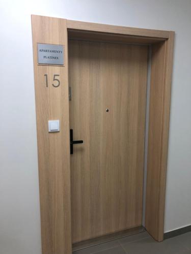 Una puerta de madera con un cartel en Apartamenty Platinex 5, en Cracovia