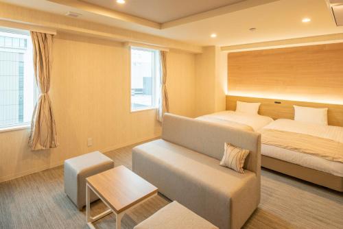 Habitación de hotel con cama y sofá en HOTEL AMANEK Asahikawa, en Asahikawa