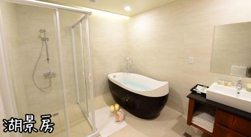 a bathroom with a shower and a sink and a bath tub at Shang Shan Ting Chao Hotel in Yuchi