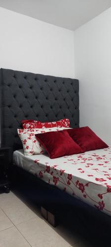 a bed with a black headboard and red pillows at Arturo Apartamento Con hermosa vista y piscina in Armenia