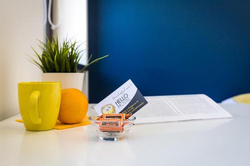 a table with a book and an orange and a cup at Hello Hostel & Apartments in Bielsko-Biala