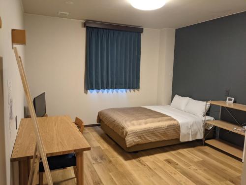 1 dormitorio con cama, escritorio y ventana en Fujieda Ogawa Hotel フジエダオガワホテル, en Fujieda