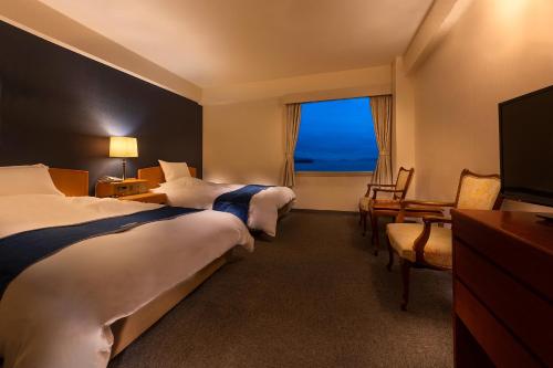 a hotel room with two beds and a window at Kurashiki Seaside Hotel in Kurashiki