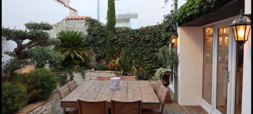 a wooden table and chairs in a garden at La Martinoise Patio in Saint-Martin-de-Ré
