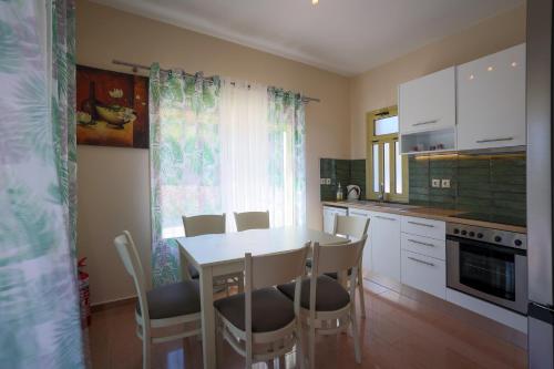 a kitchen with a table and chairs and a kitchen with white cabinets at Astra Villas in Skala Kefalonias