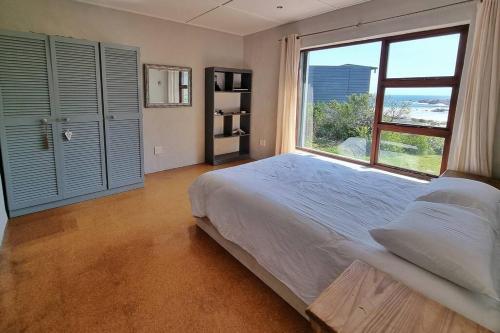 a bedroom with a bed and a large window at Hilltop Heaven, Walk to beach, Pool, Ocean & River views in Pringle Bay