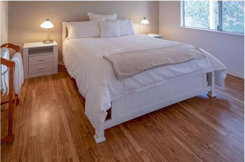 a white bed in a bedroom with a wooden floor at Abbivale Farm Cottage in Harewood