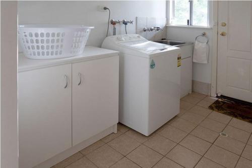 une cuisine blanche avec un évier et une machine à laver dans l'établissement Abbivale Farm Cottage, à Harewood