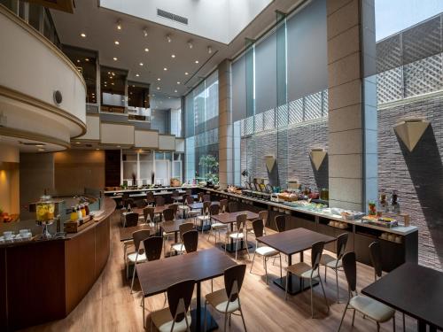 a restaurant with tables and chairs in a building at ART HOTEL Miyazaki Sky Tower in Miyazaki
