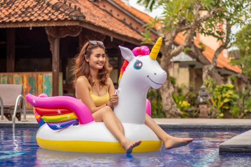 a woman sitting on a unicorn raft in a pool at Suriwathi Hotel Legian in Legian
