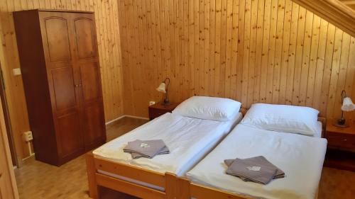 two twin beds in a room with wooden walls at Penzión pri studničke Omastiná in Omastiná
