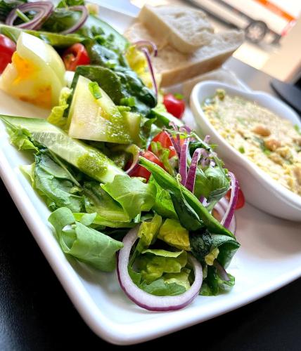 een wit bord met salade op tafel bij Aparthotel Krzywa Kamienica in Łódź