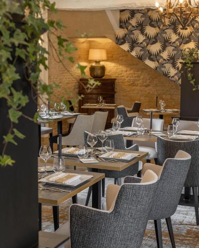 a restaurant with tables and chairs with wine glasses at Ferme de la Rançonnière - Hôtel & Restaurant in Crépon