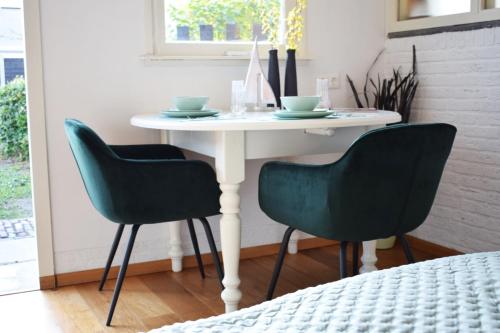 a dining room table with two green chairs around it at 't Hanennest in Nieuwerkerk