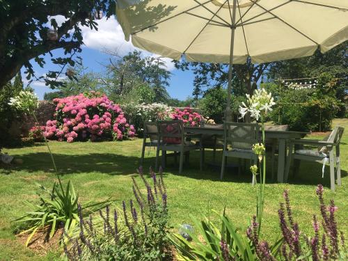 a table and chairs under an umbrella in a garden at Le Château Aspet B&B in Aspet