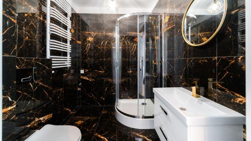 La salle de bains en noir et or est pourvue d'un lavabo et d'une douche. dans l'établissement Apartament fantazja, à Karpacz