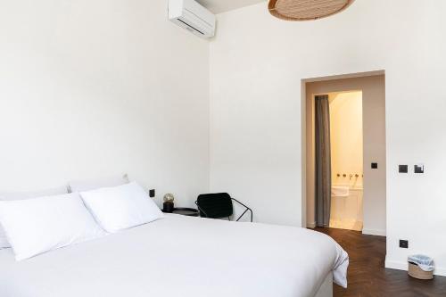 a white bedroom with a white bed and a bathroom at B'Guest Sleep & Retreat in Bruges