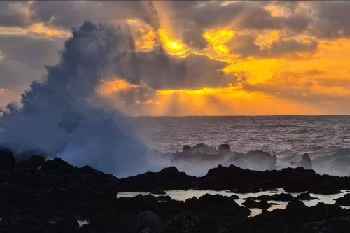 a wave erupting from the ocean with a rainbow in the sky at Monchique Islet View House T2 in Faja Grande