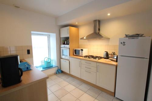 une cuisine avec un réfrigérateur blanc et une fenêtre dans l'établissement Gîtes Les Salicornes, à Dragey-Ronthon