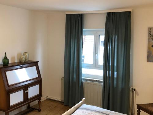 a bedroom with a window with green curtains and a television at Haus Blum in Weisweil