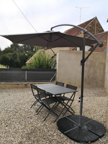 a picnic table with an umbrella and a chair at Les Fougères Du Lac in Saint-Plantaire