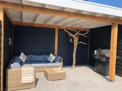 a patio with a blue couch and a grill at Country house between Egmond aan Zee & Amsterdam in Castricum