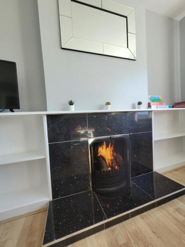 a fireplace in a living room with a fire at Knockalt Cottage in Moville