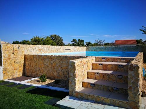 a stone wall with stairs next to a swimming pool at Tree House - 3 Casas Figueira Laranjeira Limoeiro in Sesimbra