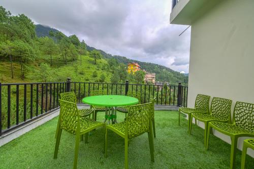 a green table and chairs on a balcony at Hotel The Paal in Shimla