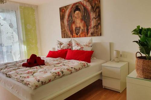 sypialnia z łóżkiem z czerwonymi poduszkami i obrazem w obiekcie Moderne Ferienwohnung direkt am Bodensee w mieście Überlingen