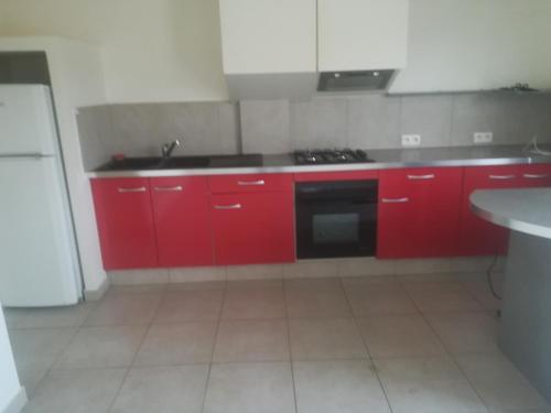 a kitchen with red cabinets and a black stove at Logement de plein pied à MIRECOURT in Mirecourt