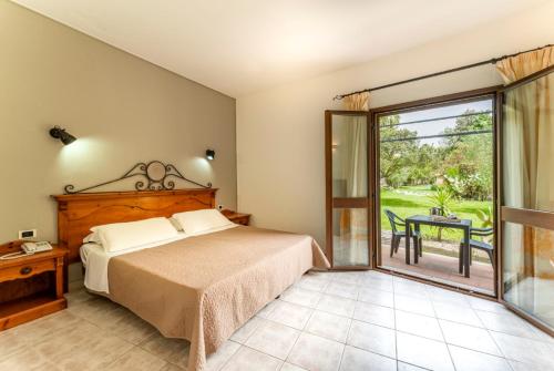 Schlafzimmer mit einem Bett und einer Glasschiebetür in der Unterkunft Horse Country Resort Congress & Spa in Arborea 