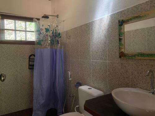 a bathroom with a toilet and a sink with a blue shower curtain at Chalé Hakuna Matata in Lumiar