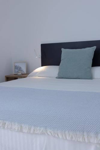 a white bed with a blue pillow on it at Island Home Fuerteventura in Corralejo