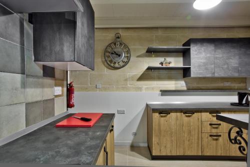 a kitchen with a counter and a clock on the wall at Chateau La Vallette - Barrakka Suite in Valletta