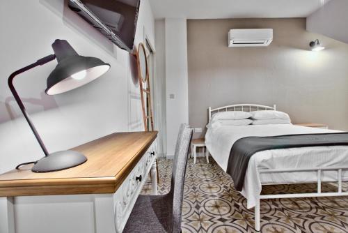 a bedroom with a bed and a desk with a lamp at Chateau La Vallette - Barrakka Suite in Valletta