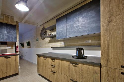 a kitchen with wooden cabinets and a counter top at Chateau La Vallette - Barrakka Suite in Valletta