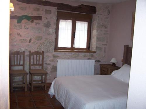 1 dormitorio con 1 cama blanca y 2 sillas en La cañada real, en Sigueruelo